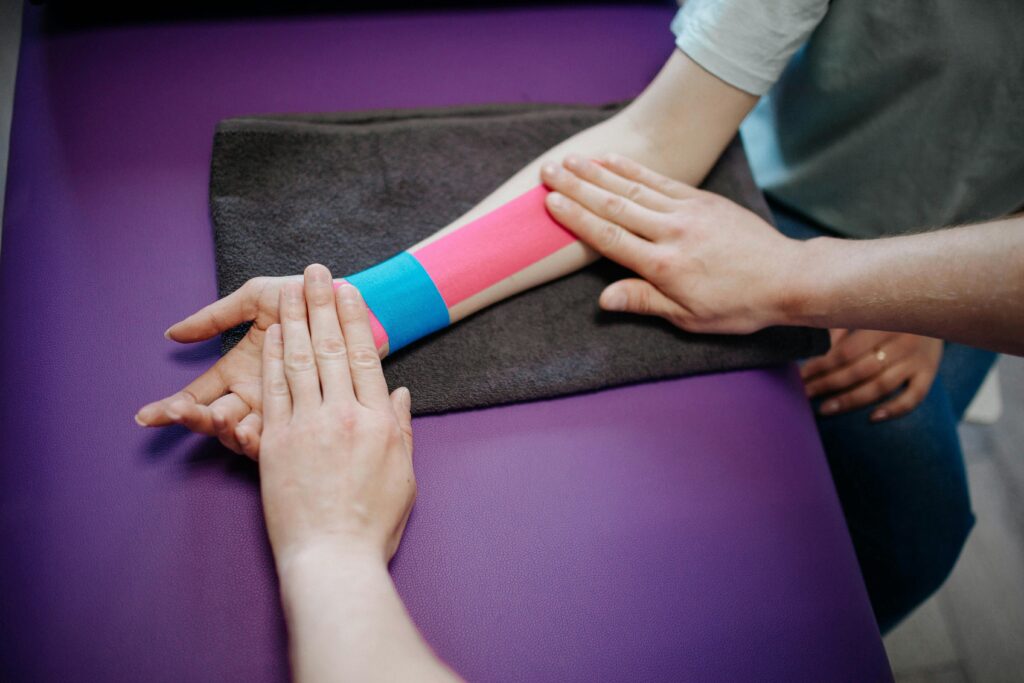 A physical therapist applying tape to injured employee at physical therapy appointment