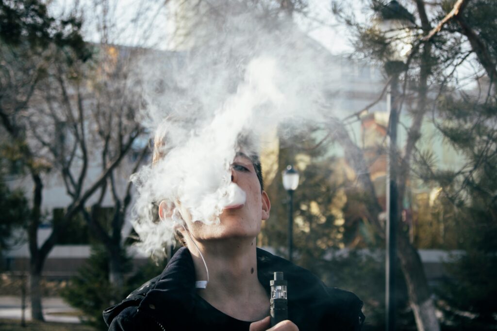 a young person inhaling cannabis vaporizer pen in the park