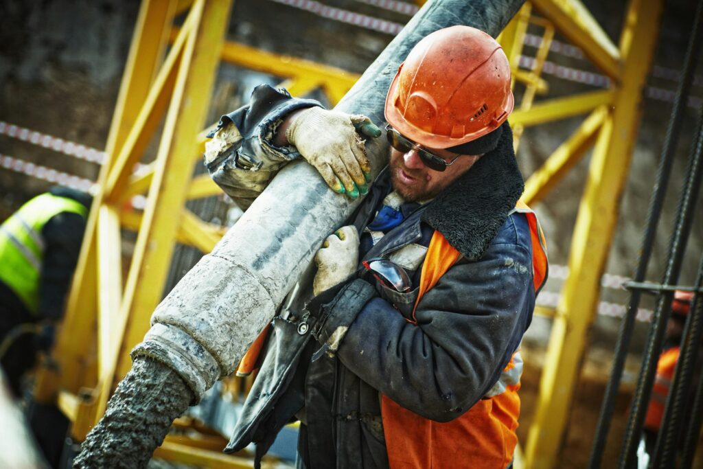 Man Carrying Gray Pipe obeying OSHA laws